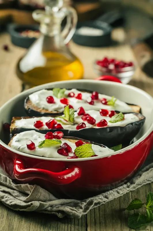 grilled eggplant with sauce and pomegranate seeds
